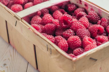 Olgun, sulu bir böğürtlen ahududunun ahşap bir kutunun içinde arka plandaki tahtalara yakın plan.