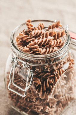 Cam bir kavanozda koyu kahverengi makarna taneleri - dikey - üst görünüm