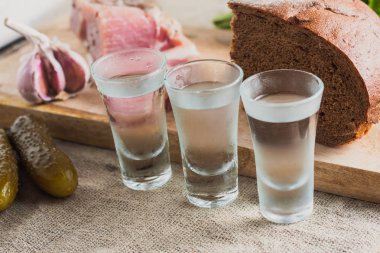 Aperatifler arka planda masada votka üç bardak - domuz yağı, sarımsak, maydanoz, ekmek, salatalık