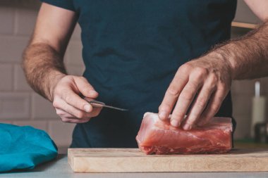 Bir adam et pişirmekle, evde yemek pişirmekle meşgul.