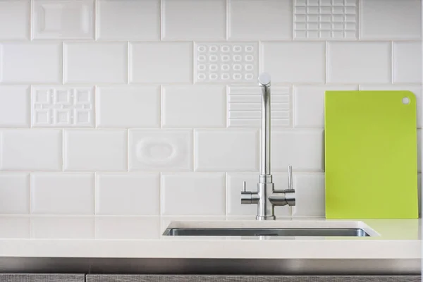 Chrome modern tap in the kitchen on a tile background, minimalism in the interior - concept decor