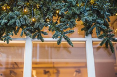 Pencerenin üzerinde köknar dalları ve çelenklerden yapılmış geleneksel Noel süsleri
