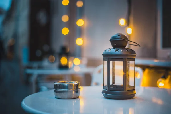 In a street cafe on the table, a cozy warm light from a vintage lamp with candles inside