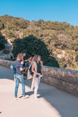 Vers-Pont-du-Gard, Gard / Occitanie / Fransa - 26 Eylül 2018: Pont du Gard Köprüsü'ndeki Avrupalı görünümlü sarışın turist kızlar muhteşem manzarayı hayranlıkla izninle