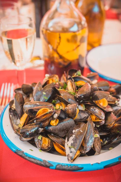 Order at the restaurant - Mediterranean cuisine - a full plate of mussels, olive oil in a glass bottle