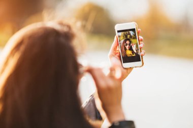 Selfie çekerken akıllı telefon ekranına odaklan. Çekici, seksi esmer.