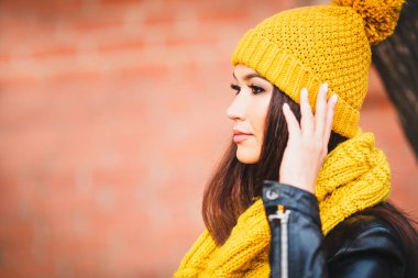 Sarı atkı ve şapkayla parlak, çekici, esmer görünümlü, sokak portresi.