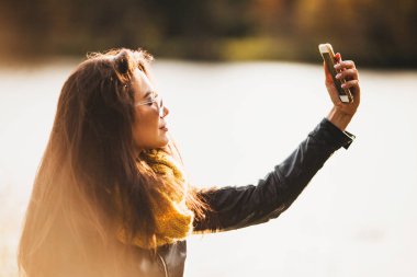 Genç, zarif Asyalı esmer, akıllı telefonuyla selfie çekiyor.
