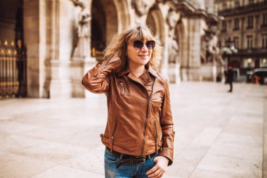 Şehir mimarisi arasında yürüyüş yapan günlük kıyafetli çekici bir sarışın.