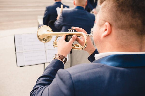 A view from the back of a trumpeter musician who plays notes on a stand