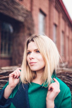 Mutlu, güzel, güzel, sarışın, sıcak yeşil ceketli, neşeli, gülümseyen bir kız.