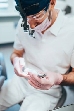 Dentist prepares a nozzle for a drill - preparing a dental office to receive a patient for tooth treatment