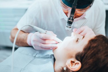 Tooth filling - dentist prepares a diseased tooth - close-up of head light