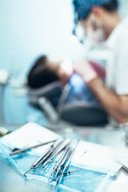 Dentist tools on table on blurred background doctor and patient in defocus