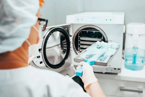 Autoclaving - Sterilization of medical instruments - a nurse loads a tray of instruments for sanitization into an autoclave