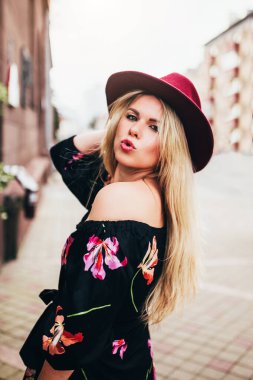 Açık hava şapkalı, hafif rüzgarlı sarışın kadın hava öpücüğünü canlandırıyor. Genç, seksi kadın.