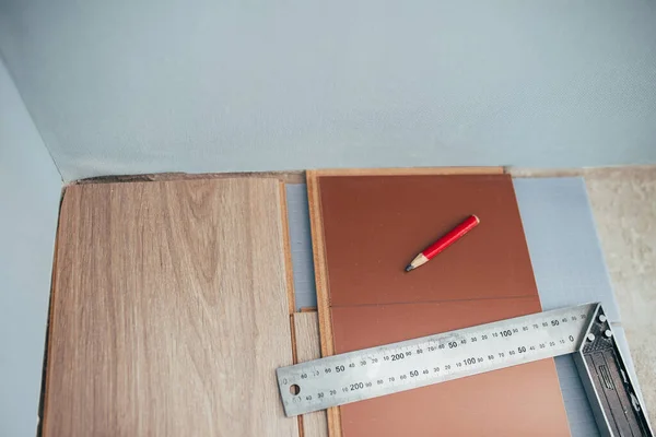 快速方便地安装地板工具 工作用金属正方形和铅笔标出切割线 — 图库照片