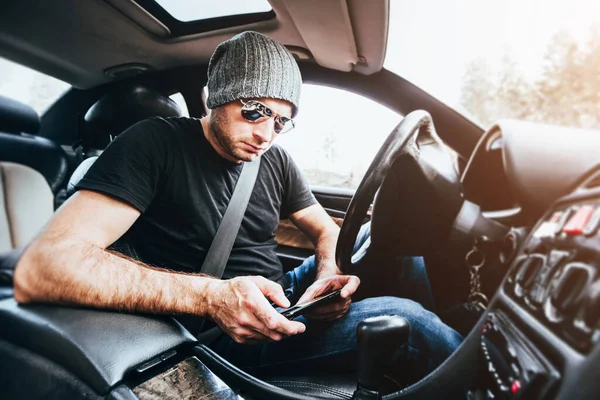 Hombre Caucásico Gafas Sombrero Sostiene Teléfono Inteligente Sus Manos Mientras — Foto de Stock