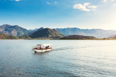 Virpazar, Karadağ - 19 Ağustos 2020: Güneşli bir günde göl boyunca gezen turistler - huzurlu bir manzara