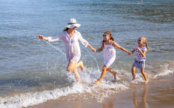 母亲带着两个小女儿在沙滩上奔跑 — 图库照片