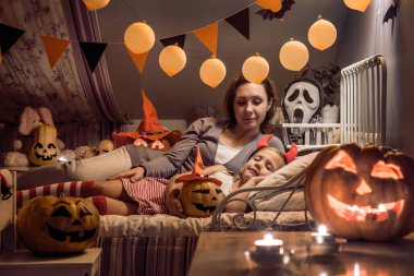 Cadılar Bayramı için dekore edilmiş çocuk yatak odasında uyuyan kızı anne bakar