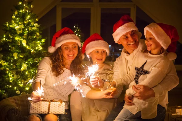 幸せな家族がクリスマス ツリーの下のベンガル蝋燭をつけた — ストック写真