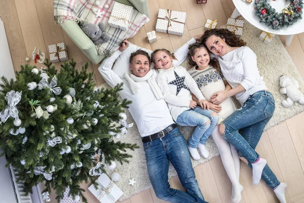 人の子供と幸せな家庭はカーペットの上の贈り物にクリスマス ツリーの下にあります 上からの眺め — ストック写真