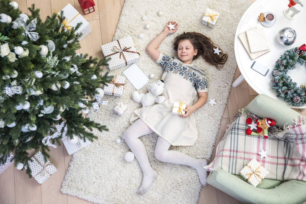 little girl with  present  sleeping under Christmas tree