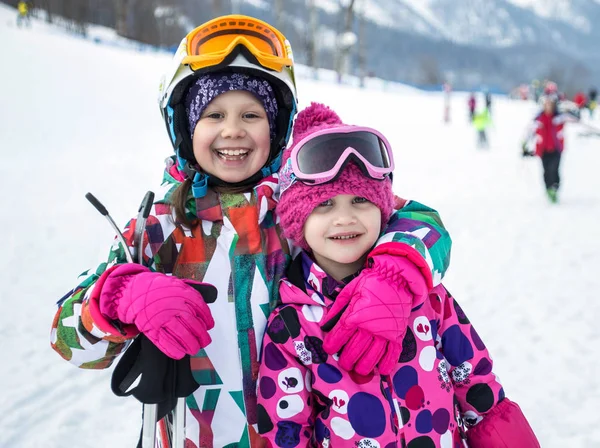 Portrait of little girls on alpine skiing skating on slope in ski resort