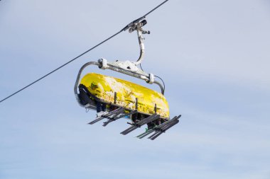 Sandalyedeki sporcular kar kaplı dağların arasında bir kayak merkezinde.