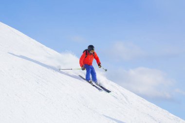 Dağlarda karlı bir yolda kayak yapan bir adam