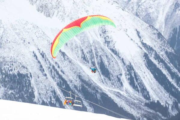 人のインストラクターと雪の山の空を飛んでいる乗客とパラグライダー — ストック写真
