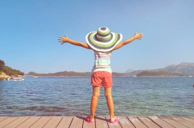 büyük şapkalı küçük kız sahilde zevk ve deniz tesisi