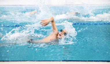 Küçük çocuk havuzda yüzüyor. 