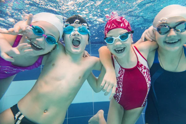 Niños nadando en la piscina bajo el agua. —  Fotos de Stock