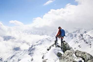 Dağların tepesindeki dağcı, karlı dağların arka planında.