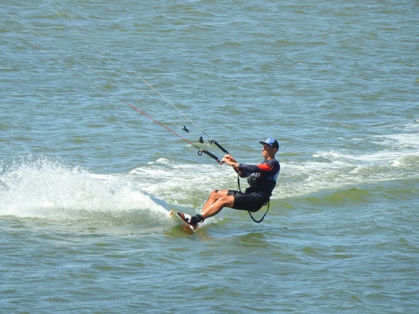 若いスポーティな男が砂浜から海でカイトサーフィン — ストック写真