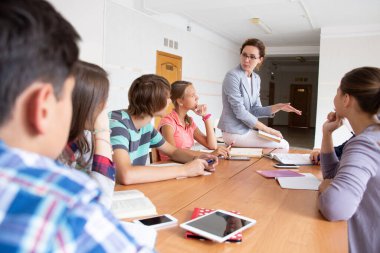 Bir grup öğrenci okuldaki öğretmenleri dinliyor.