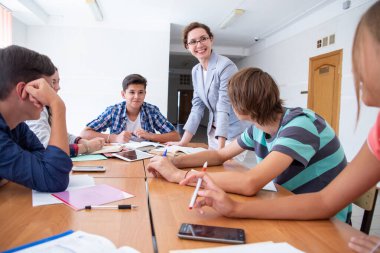 Bir grup öğrenci okuldaki öğretmenleri dinliyor.