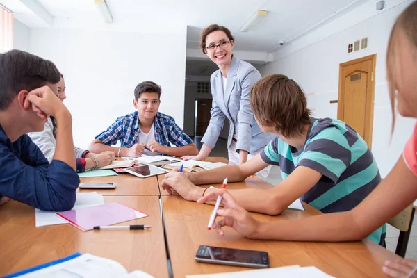 Bir grup öğrenci okuldaki öğretmenleri dinliyor.