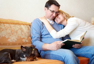 Olgun bir çift küçük bir köpekle kanepede iyi vakit geçiriyor.