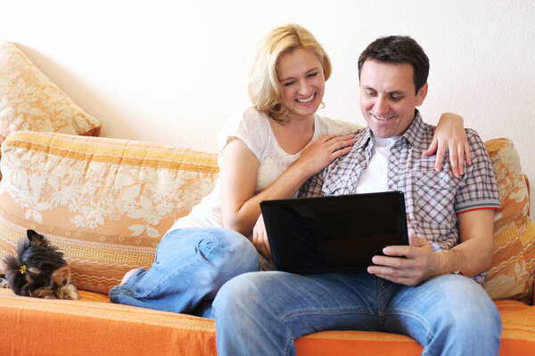 Mature couple came to the Internet on a laptop sitting on the couch at home