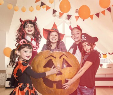 Kostümlü bir grup komik çocuk Cadılar Bayramı partisini birlikte kutluyor.