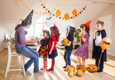 Genç anne cadılar bayramında çocuklara şekerle davranır.