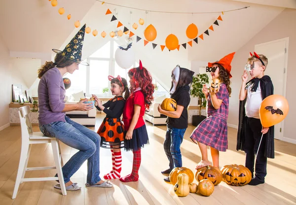 Genç anne cadılar bayramında çocuklara şekerle davranır.