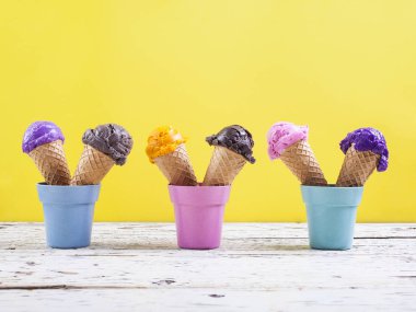 Yaban mersini, çikolata, çilek ve portakal dondurma waffle içinde çeşitli topları sarı zemin üzerine çeşitli dondurma kaşık toz