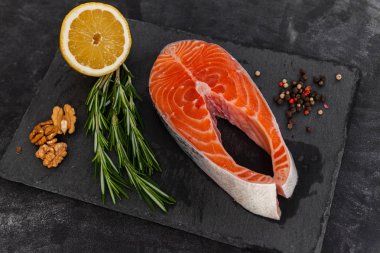 Siyah taş tahtada kırmızı balık, malzemeler, somon balığı, üst manzara.