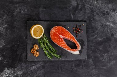 Siyah taş tahtada kırmızı balık, malzemeler, somon balığı, üst manzara.