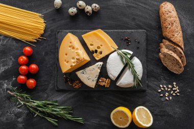 Siyah masanın üstünde farklı besin maddeleri olan peynir koleksiyonu.