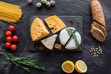Siyah masanın üstünde farklı besin maddeleri olan peynir koleksiyonu.